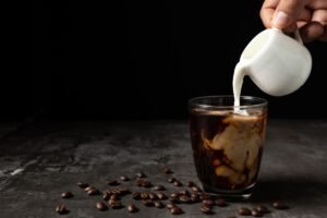 Top Iced Coffee Recipes and Tips to Stay Cool and Energized | ibobeans Pouring milk into iced coffee glass recipe by ibobeans