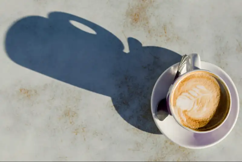 Flat White Coffee: Your Super Easy Guide to This Tasty Drink Flat white coffee with latte art in sunlight, evoking 1980s café origins.