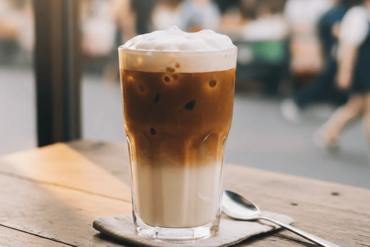 Thai Coffee Recipe: How to Make Authentic Gafae Yen at Home (Beginner Guide) Authentic Thai iced coffee recipe in tall glass showing beautiful layered effect with dark coffee and creamy milk on wooden table